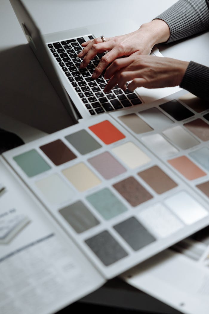 hero-img Hands typing on a laptop next to a color swatch book, ideal for design and creativity themes.
